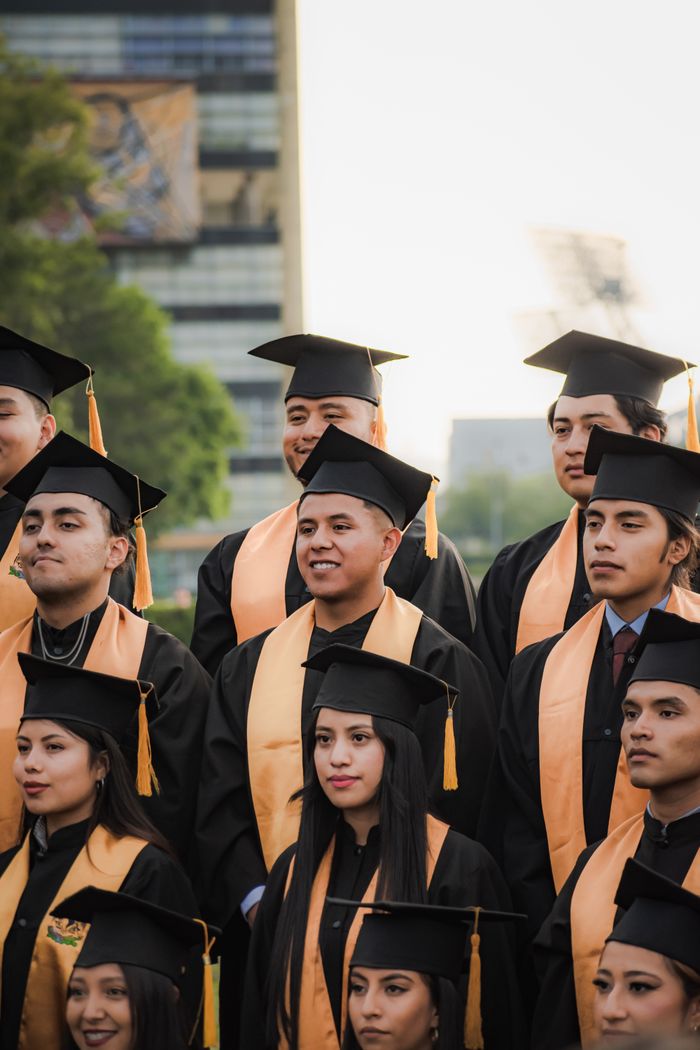 A group of diverse university students celebrating graduation outdoors.