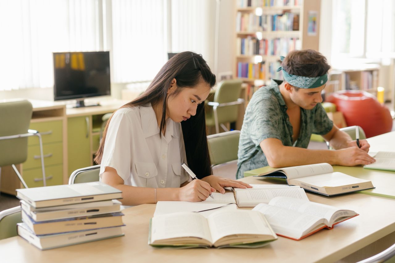 services-01 College students studying and taking notes in a library setting.